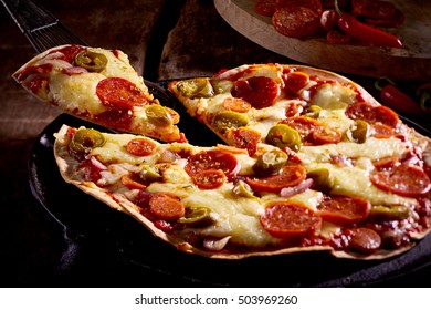 Traditional Tex Mex Tortilla Pizza Topped With Chorizo Italian Sausage, Cheese And Tomato Seasoned With Hot Peppers With A Single Slice Being Served