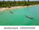 Traditional Thai Longtail fishing boats anchored off a small, palm tree lined tropical beach (Khao Lak, Thailand)