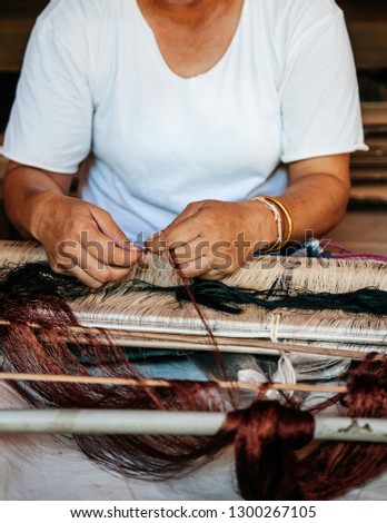Traditional Thai north eastern style loom details woman hands weaving Thai silk with wooden reeds