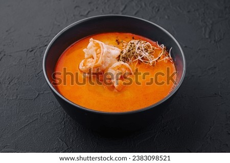 Traditional Thai soup Tom Yam in black bowl