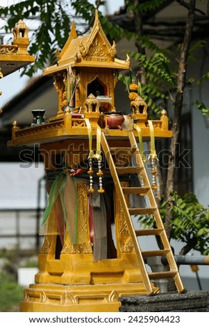 Traditional Thai Spirit House Adorned with Offerings and Ribbons
