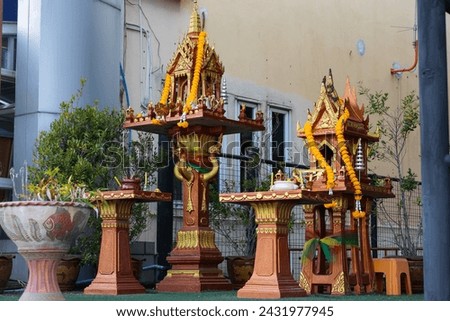 Traditional Thai Spirit houses in Pattaya, Thailand. Spirit House with Deities and Offerings decorated orange flower garlands