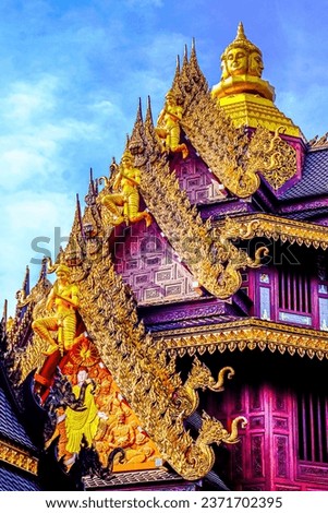 Traditional Thai Style Animal Gods Carved on Roof Decorations Against a Blue Sky