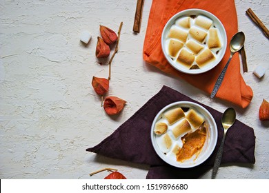 A traditional Thanksgiving dish, sweet potato casserole with marshmallows in portioned forms on a light concrete background. American cuisine. Thanksgiving Recipes. Top view, copy space.