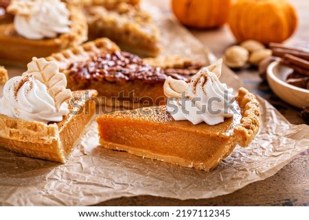 Traditional Thanksgiving pies slices on parchment paper, pumpkin and pecan pie