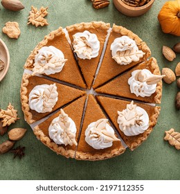 Traditional Thanksgiving Pumpkin Pie Cut Into Slices Overhead View On A Green Surface