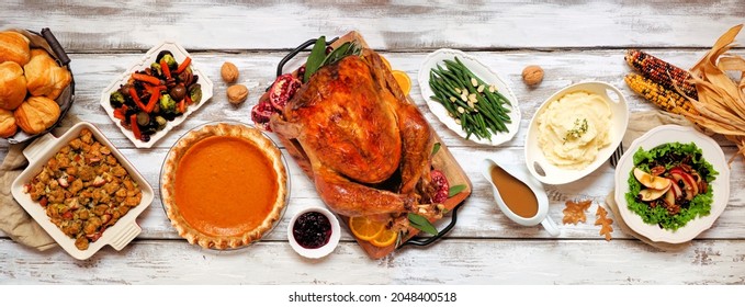 Traditional Thanksgiving turkey dinner. Above view table scene on a rustic white wood banner background. Turkey, mashed potatoes, stuffing, pumpkin pie and sides.