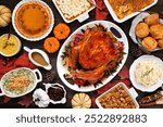 Traditional Thanksgiving turkey dinner. Top view table scene on a rustic dark wood background. Turkey, mashed potatoes, stuffing, casseroles, pumpkin pie and sides.