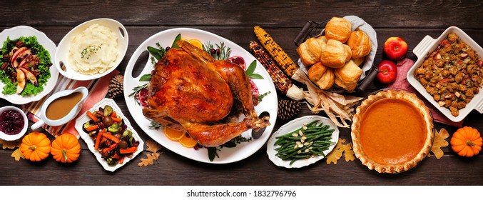 Traditional Thanksgiving turkey dinner. Top view table scene on a dark wood banner background. Turkey, mashed potatoes, dressing, pumpkin pie and sides.
