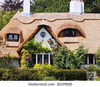 Traditional Thatched English Village Cottage And Garden With Climbing Roses