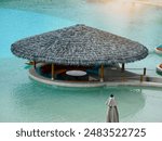 A traditional thatched hut is located within a swimming pool