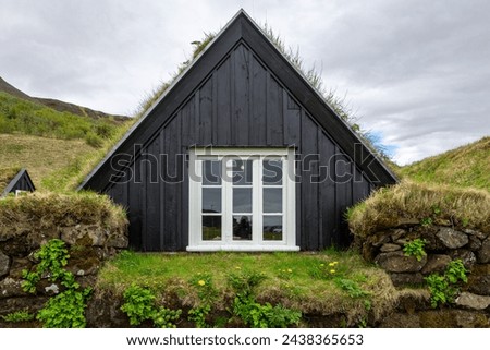 Traditional turf house in Skogar Open Air Museum, black wooden facade residential building with roof covered with turf and moss, white window frames, Iceland.