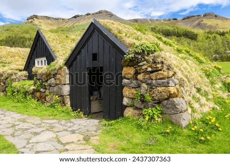 Traditional turf house village in Skogar Open Air Museum, black wooden facade residential buildings with roofs covered with turf and moss, Iceland.