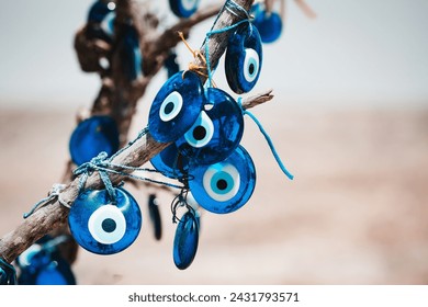 Traditional Turkish amulet Evil Eye or blue eye (Nazar boncugu) on tree brunch. Traditional Turkish amulet and souvenir. Close up, defocused background, copy space. Cappadocia, Turkiye (Turkey)
