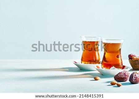 Traditional Turkish black tea in glass on saucer with dates on white background with copy space. Wide banner.