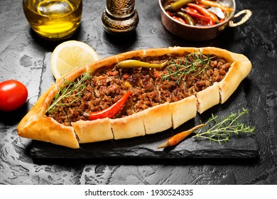 Traditional Turkish cuisine. Turkish pizza on Pita with ground beef on black stone background.