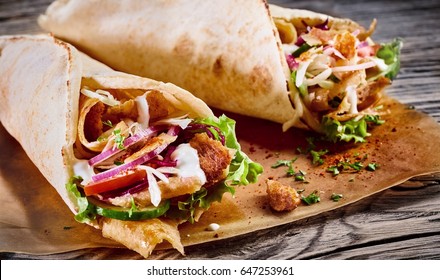 Traditional Turkish doner kebab in a tortilla wrap with fresh vegetable ingredients served on brown paper in a close up view on the filling