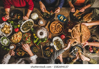 Traditional Turkish family celebration dinner. Flat-lay of people eating Turkish salads, cooked vegetables, meze starters and borek pie and drinking raki drink, top view. Middle Eastern cuisine - Shutterstock ID 1582694137