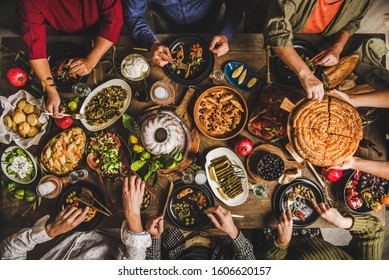 Traditional Turkish family celebration dinner. Flat-lay of people feasting at table with Turkish salads, cooked vegetables, meze starters, pastries and raki drink, top view. Middle Eastern cuisine - Shutterstock ID 1606620157