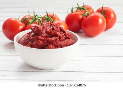 Traditional turkish tomato paste in bowl or spoon with fresh tomatoes on wooden table, homemade healthy food