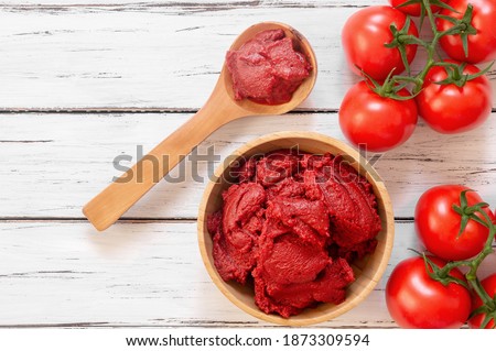Traditional turkish tomato paste in bowl or spoon with fresh tomatoes on wooden table, homemade healthy food