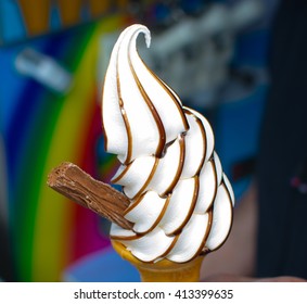 traditional UK Mr whippy style soft scoop ice cream cone with flake and chocolate syrup and rainbow in the background