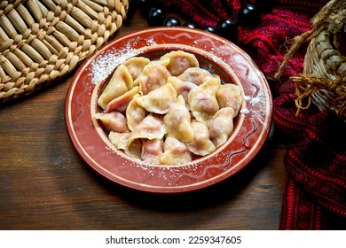Varenyky dulce ucraniano tradicional con cerezas y azúcar en polvo en un plato de arcilla. Gastronomía de Ucrania