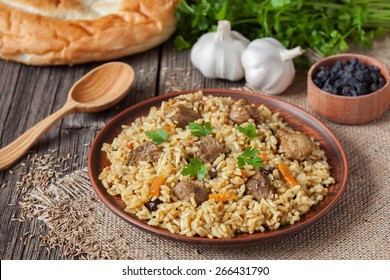 Traditional uzbek meal called pilaf. Rice with meat, carrot and onion in vintage plate on wooden background - Powered by Shutterstock