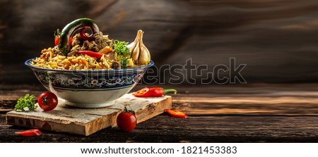 Traditional uzbek meal called pilaf. Rice with meat, carrot and onion in plate with oriental ornament, Uzbek oriental cuisine. Long banner format. space for text.