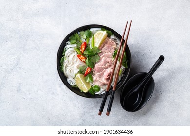 Traditional Vietnamese Soup Pho Bo With Beef And Rice Noodles On A Concrete Background, View From Above