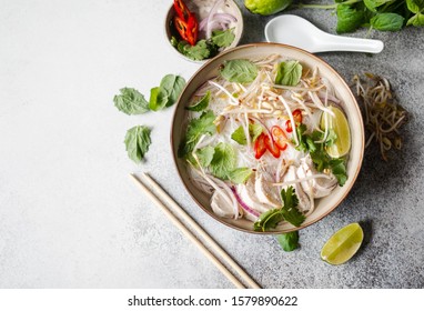 Traditional Vietnamese soup- pho ga in bowl with chicken and rice noodles, mint and cilantro, red onion, chili, bean sprouts and lime on grey background.  Asian food. Copy space. Top view  - Powered by Shutterstock