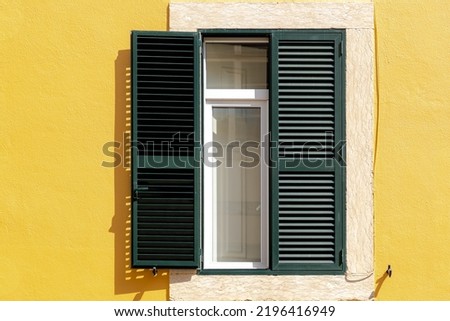 Traditional and vintage Portuguese house style, Green wooden louver window, Yellow painted cement concrete wall, Lisbon is capital city of Portugal.