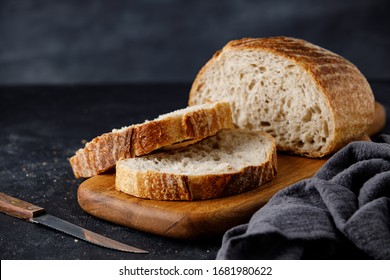 Traditional wheat freshly rustic baked bread with sliced on wooden cutting board and towel. Artisan sourdough bread with knife.  - Powered by Shutterstock