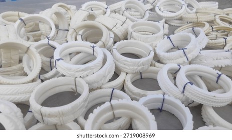 Traditional white conch shell bangles known as Shakha are stacked in a workshop during the manufacturing process, displaying intricate hand-carved patterns and authentic cultural craftsmanship.