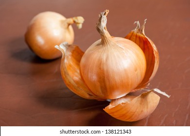 Traditional white onion with brittle and dry outer layers, two onion bulbs lying on wooden brown table, healthy vegetables, horizontal orientation, studio shot, nobody.