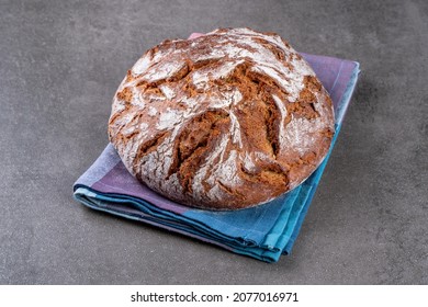 Traditional wholemeal rye bread in country style. Single object on a checkered napkin. Top view, copy space.