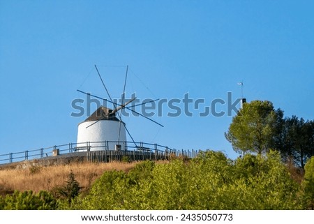 Traditional windmill on top of a hill on a clear day in Sanlucar de Guadiana, Spain. Restored traditional mill with its whitewashed walls and typical conical roof.