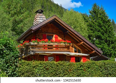 Traditional Wooden Alpine Chalet With Geranium Flowers On The Window In Summer