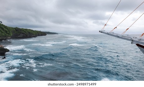 traditional wooden boat sails past a rugged coastline, with turquoise waters crashing against the rocky shore. - Powered by Shutterstock