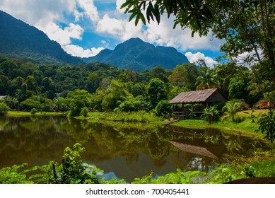 Traditional Wooden House Near The Lake And Mountain In The Background In The Kuching To Sarawak Culture Village.Borneo, Malaysia