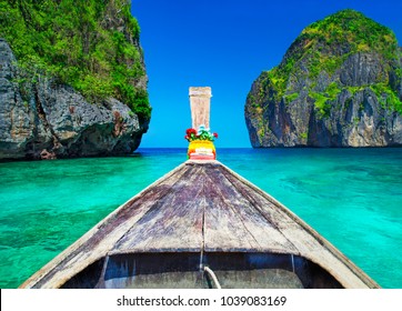 Traditional wooden longtail taxi boat nose with decoration flowers and ribbons at Maya Bay beach against steep limestone hills. Main Thailand tourist attraction background, Ko Phi Phi Leh Island