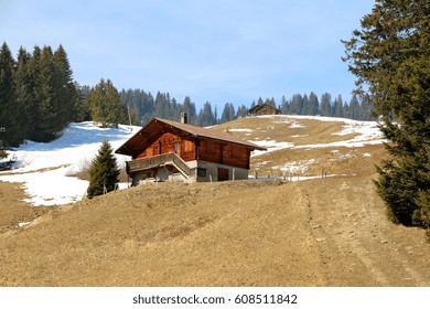 Traditional wooden Swiss cottages in a rural, alpine setting.