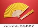 Traditional yellow Asian hand fans on red background