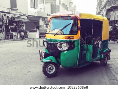 Traditional yellow green tuk tuk taxi on the street. Indian public transport on the streets of new Delhi. Tricycle vintage retro motorcycle