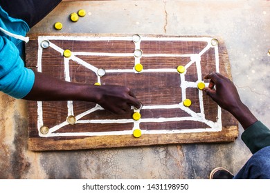 Traditonal African Strategy Board Game Know As Morabaraba Or Muravarava Being Played On A Wooden Board Using Bottle Cap Pieces