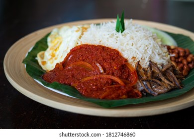 Traditonal Malaysia Asian Food Nasi Lemak On A Banana Leaf In A Wooden Bamboo Plate. Side View Of Sambal.