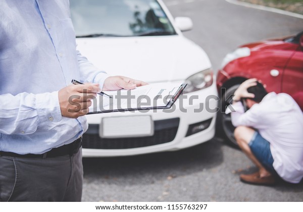 Traffic Accident\
and insurance concept, Insurance agent working on report form with\
car accident claim\
process.