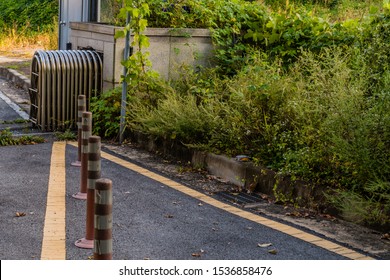 Traffic Bollards In Front Of Metal Folding Entrance Gate Located In Rural Industrial Park.