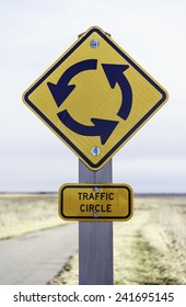 Traffic circle sign posted by pavement (shallow depth of field) स्टॉक फोटो