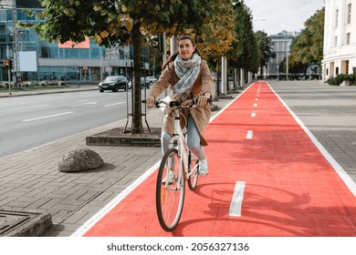 traffic, city transport and people concept - woman riding bicycle along red bike lane or two way road on street